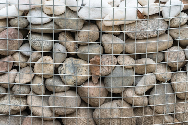 Rounded stones behind metal mesh