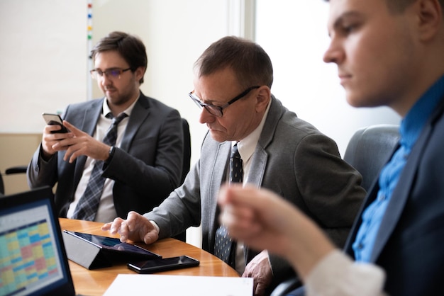 Roundtable meeting of business partners Business people talking and using laptops and phone