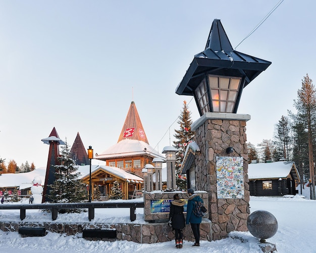 로바니에미, 핀란드 - 2017년 3월 5일: 크리스마스 트리가 있는 산타 마을의 산타클로스 사무실에 있는 커플. 겨울에 북극권에 있는 핀란드 라플란드. 배경에 사람들