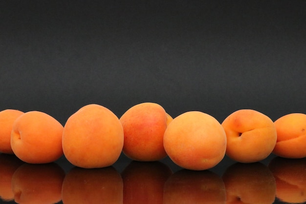 A row of apricots on a black background