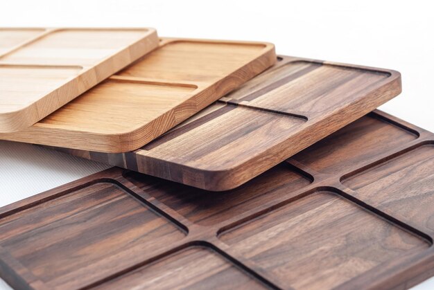 Row arrangement of carved wooden trays of different colors and timber on white background