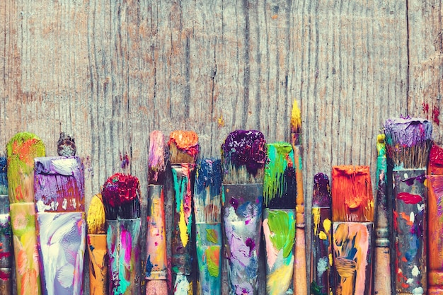 Photo row of artist paint brushes closeup on old wooden background