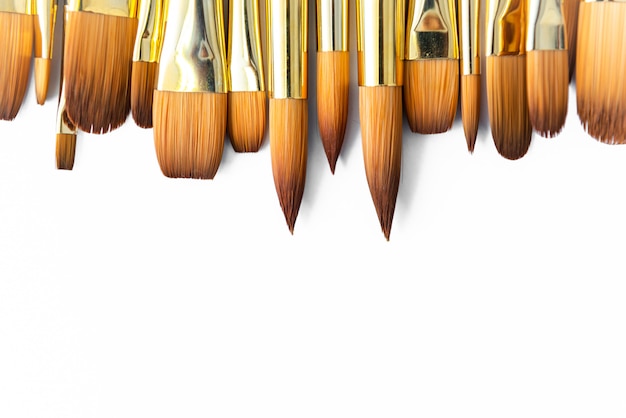 Row of artist paint brushes closeup on white background, paintbrushes for wallpaper.