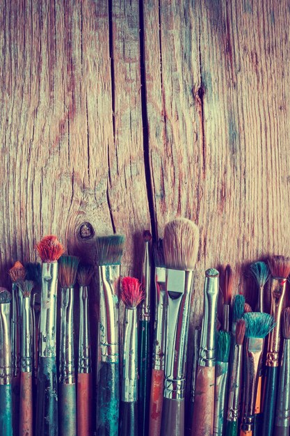 Row of artist paintbrushes closeup on old wooden rustic background retro styled