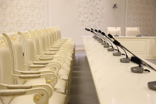 A row of chairs in a conference hall with microphones in the background