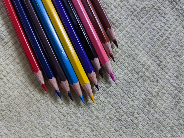 A row of colored pencils are lined up on yellow background