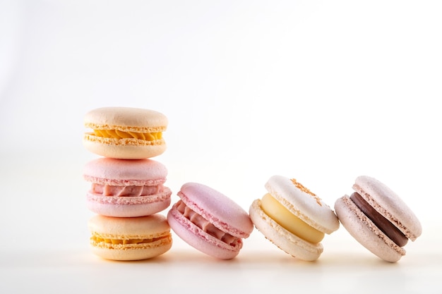 Riga dei macarons o dei macarons francesi pastelli variopinti su fondo bianco e rosa