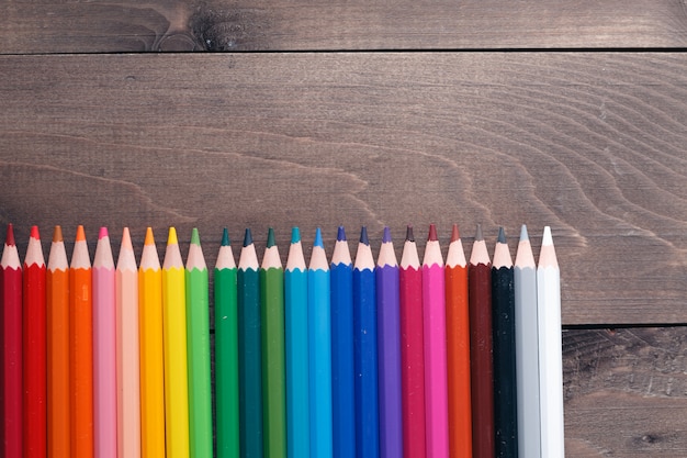 Row of colour pencils on wooden table