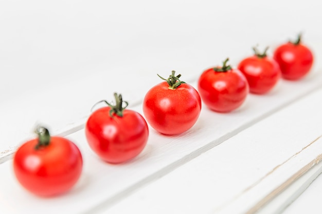 白い木製のテーブルにおいしいチェリートマトの行。対角線。健康的な食事と菜食主義。テキストのためのスペース。