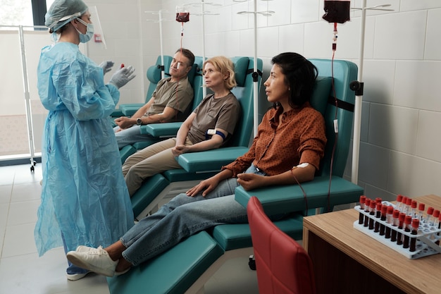 row of donors sitting in hospital ward during hemotransfusion procedure