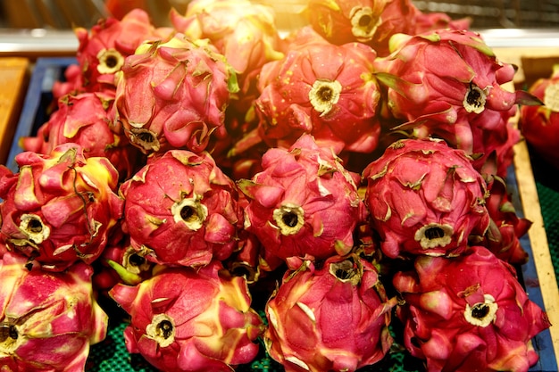 Row of dragon fruits at market counter.