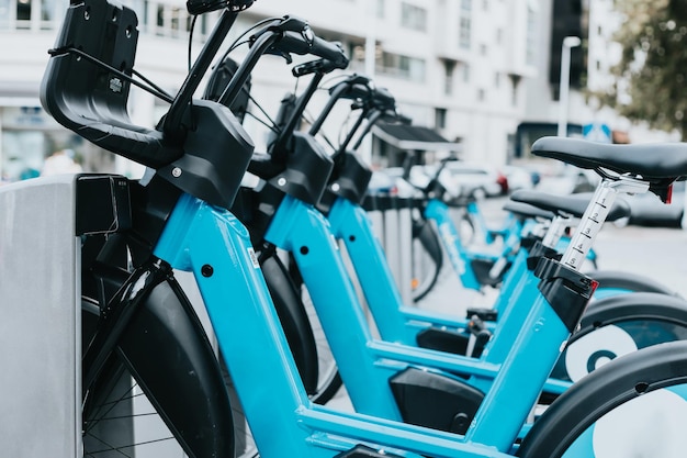 充電しながらもたれかかる電動自転車や公共の自転車の列 街を訪れたり移動したりするための新しい公共交通機関やエコ交通手段 代替の環境に優しい車両のロックを解除する新しいシステムに駐輪された自転車