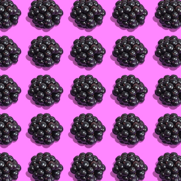 Photo row of fresh blackberries on pink background