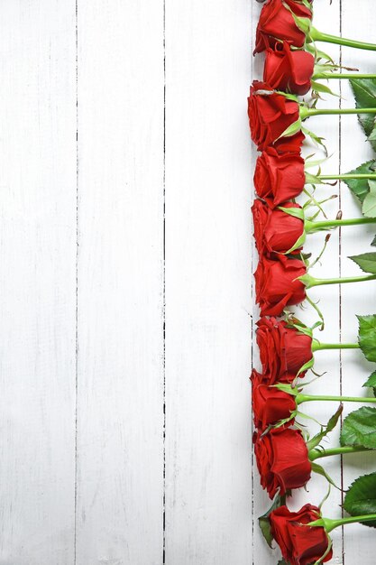 Row of fresh red roses on wooden background