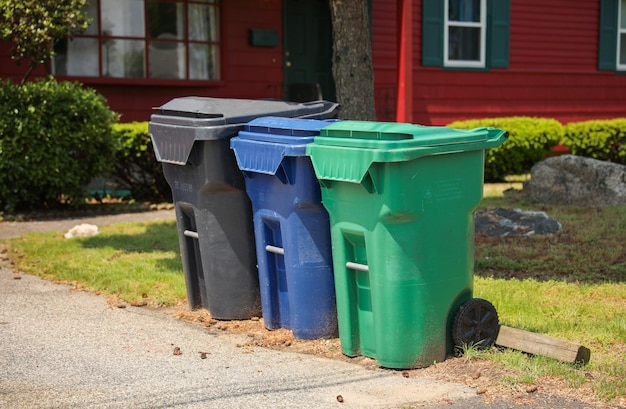 Photo a row of garbage cans are lined up in front of a red house.