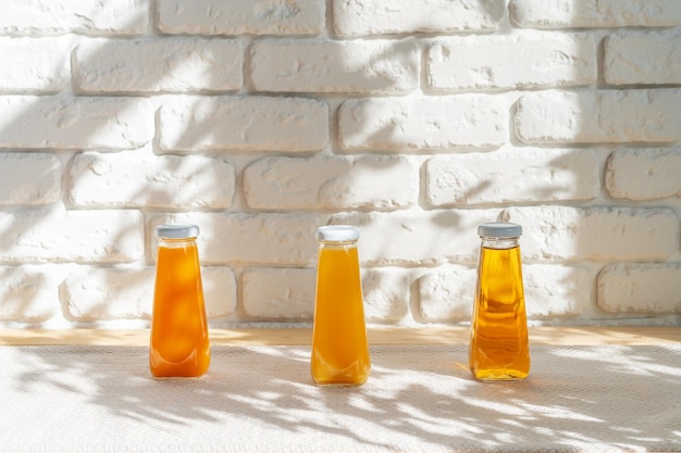 Row of glass bottles of different juices against white brick wall