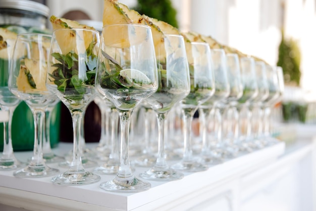 A row of glasses of pineapples are lined up on a bar.