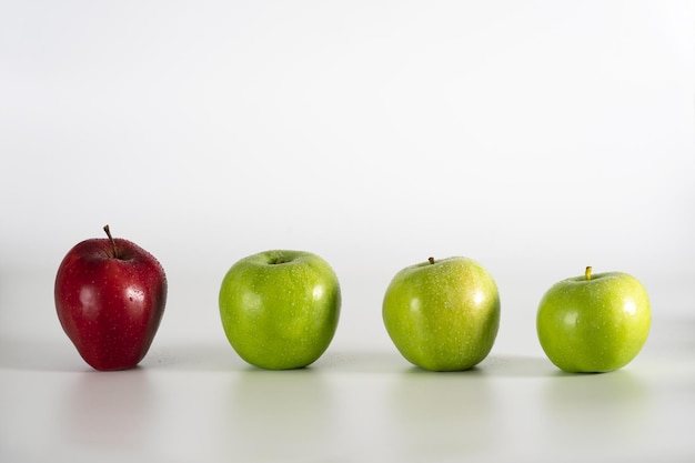 A row of green apples and one red apple among them.