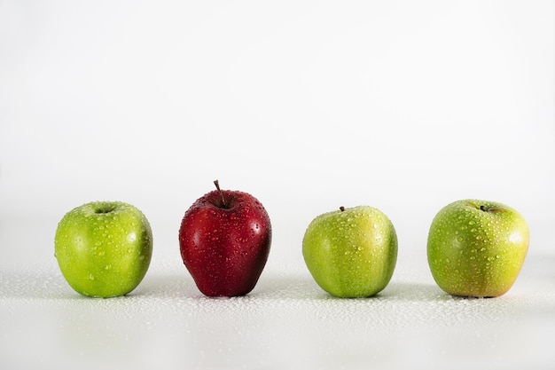 A row of green apples and one red apple among them.