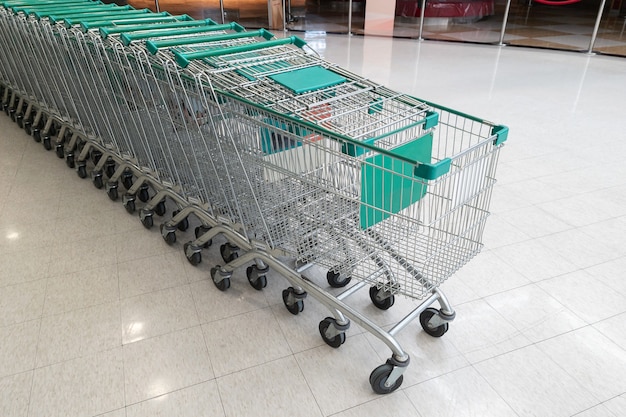 Fila di servizio di carrello vuoto verde per il cliente in supermercato