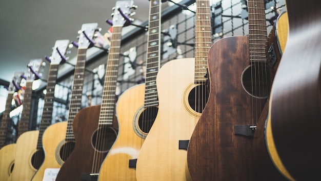 ряд гитар, выставленных на продажу, висит в музыкальном магазине