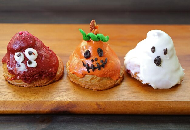 Row of halloween ghosts shaped sugar glazed croissants on wooden breadboard