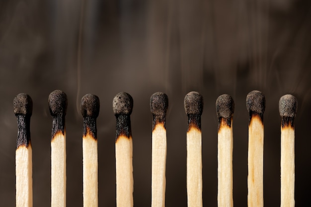 Row of matches with burned heads isolated on black background