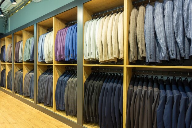 A row of mens suits jackets hanging on a rack for display