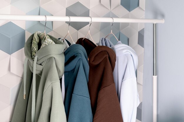 Row of multi-colored knitted hoodies, sports sweaters hanging on a hangers in an atelier or sportswear of Retail  store  close-up. pastel cold colors.