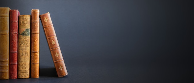 Row of old books isolated on dark background banner