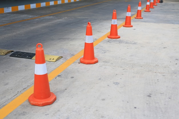 Row of orange rubber traffic cone placed in road.