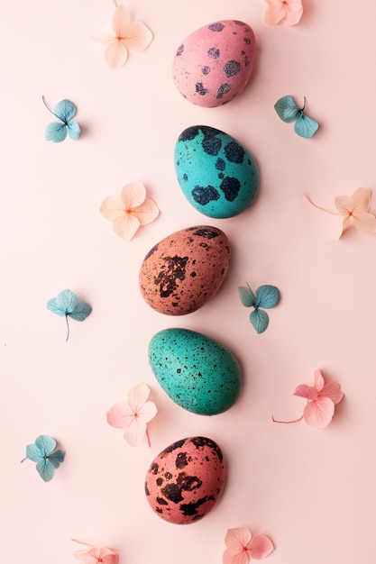 Row of painted quail eggs and hydrangea flowers pink and blue eggs on pink background Easter greeting card