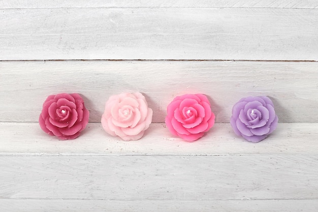 A row of pink and purple flowers on a white wooden table.