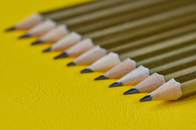 Row of plain pencils on yellow surface