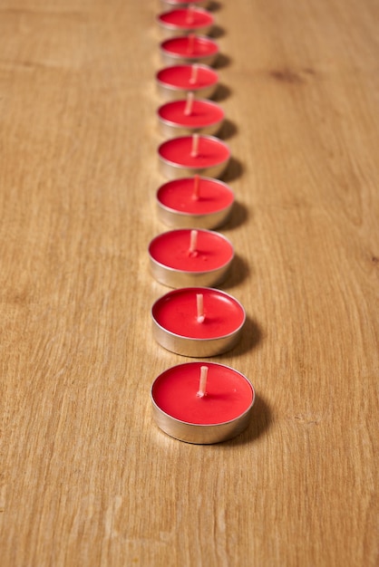 A row of red candles on a wooden table