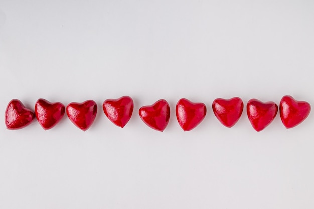 A row of red souvenir hearts lies on a white background copy space