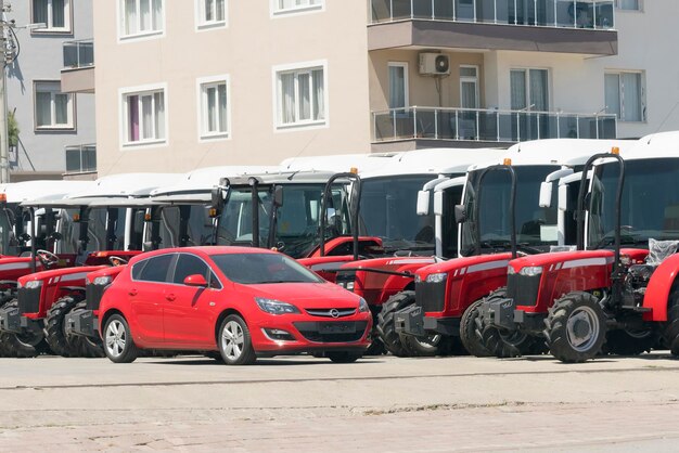 Row of red wheel tractors and a red car on a city street