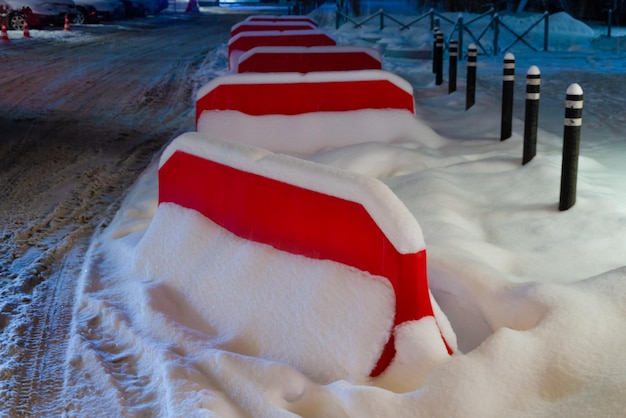 A row of red and white seats covered in snow.