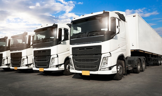 Row of semi trailer trucks parking at blue sky industry road
freight truck transport and logistics