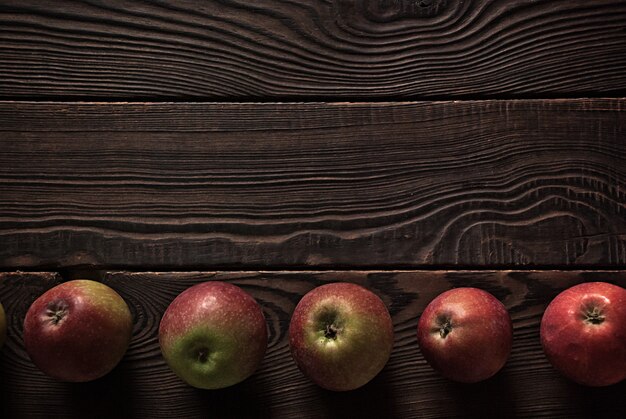 Photo row of several red apples on a wooden surface