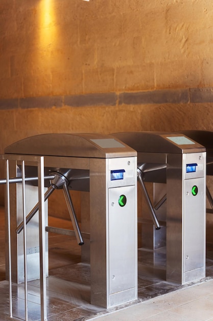 a row of sleek stainless steel turnstiles each featuring green lights
