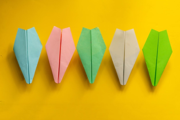 Row of some color paper planes handmade origami on the tables