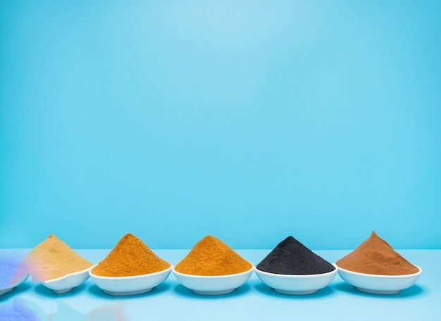 A row of spices are on a blue table.