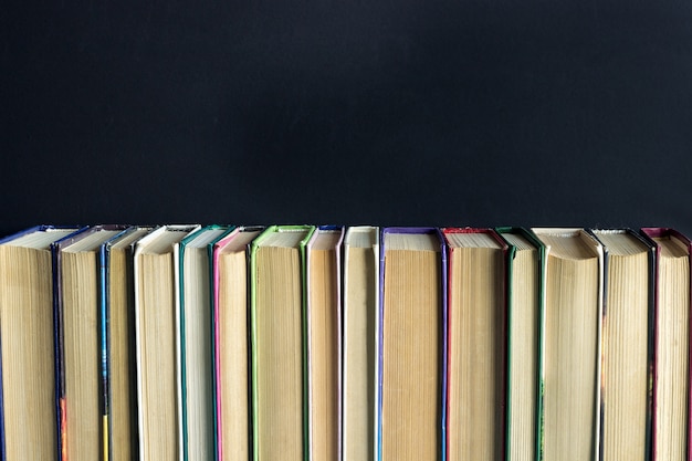 Row stack of old books on background black chalkboard