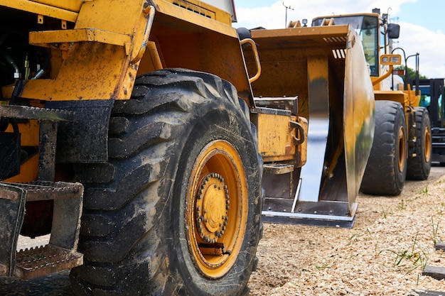 Photo row of standing heavy construction wheeled bulldozers close up