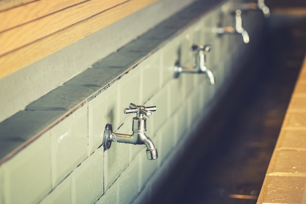 row of steel taps into a large bathroom