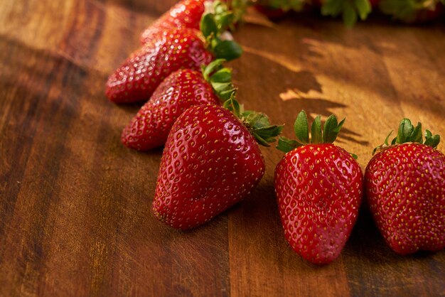 A row of strawberries on a wooden cutting board