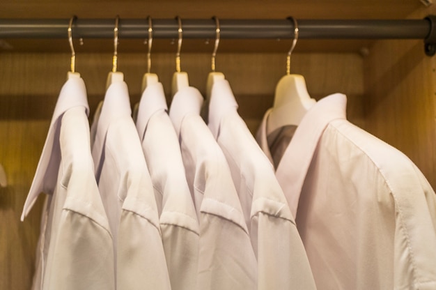 対称に掛けられた白いメンズシャツの列