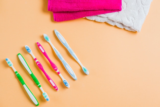 Fila di spazzolino da denti con asciugamano rosa e bianco su sfondo colorato