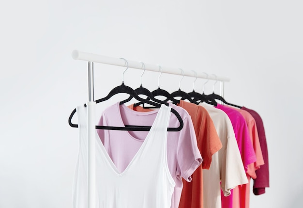 row of tshirts on a hanger against a background of a white wall hanger